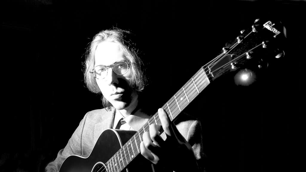 Black and white portrait of Eli playing guitar